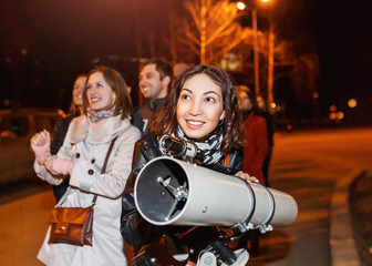 Group of people at night looks at the starry sky in a large professional telescope and smiles © EdNurg