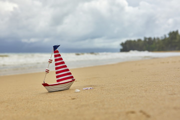 Fototapeta na wymiar Small toy sailing yacht on the beach