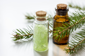 fir branches and spruce bath salt and aroma oil on white table background