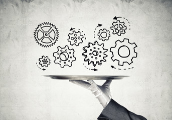 Waiter hand with empty silver tray and drawn gears concept