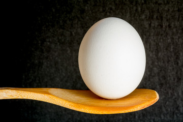 An egg balanced on a wooden spoon.