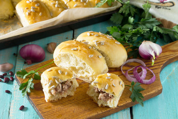 Homemade pies with meat and beans (minced meat and yeast dough) on a wooden table.