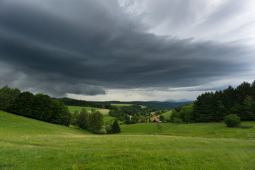 Thunderstorm with rain coming to green meadows in black forest