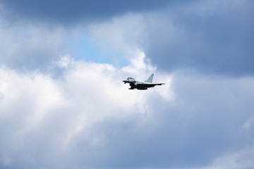 Modern jet fighter flying high in the sky. Dramatic sky with clouds.
