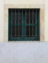 Modern closed window with vintage bars on clear wall, vertical orientation