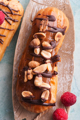 Eclairs with peanuts, chocolate icing and raspberries