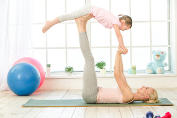 Young mother and daughter exercise together indoors