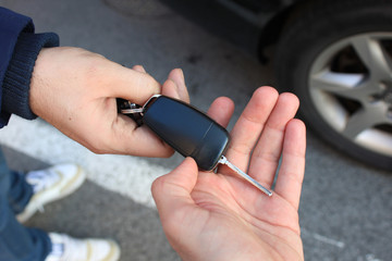 car sales. one person sells car and gives the key to the new owner