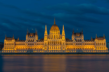 beleuchtetes Parlamentsgebäude in Budapest mit Donau im Vordergrund