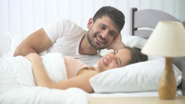 The happy man and woman kissing in the bed