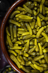 Pickled gherkins in a clay pot, from top, whole cucumbers, cornichons