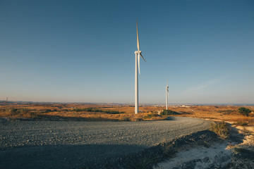 Two windmills by roadside in a rural landscape in Cyprus