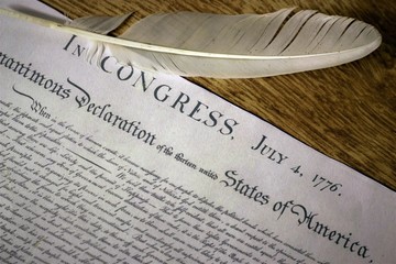 Declaration of Independence with feather quill on wood surface