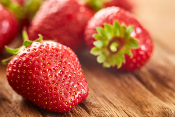 Close-up of the fresh red strawberries on the brown wooden table.