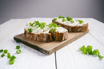 Bread with butter and spread. Concept of healthy breakfast. Spring onion, Vegetables. Wooden white table with copy space