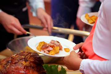 waiter serves roasted meat and baked potatoes at the party