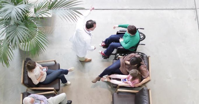 Overhead shot of Medical Doctor greeting woman in wheelchair in waiting room