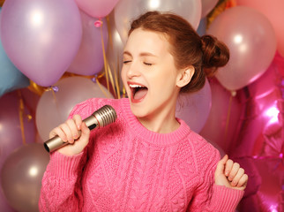 Happy singing girl. Beauty woman with microphone over  backgroun