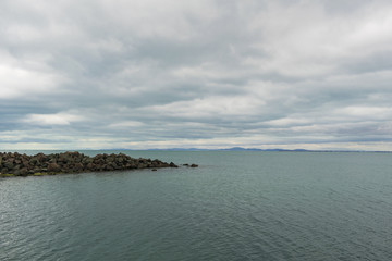 Cloudy day at sea with rocks and calm water