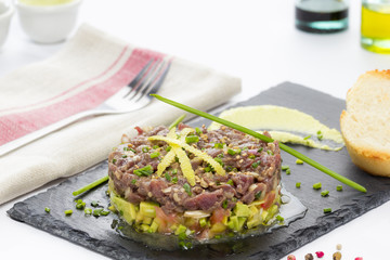 Bluefin tuna tartare on a black slate plate with avocado, served with grilled bread.
