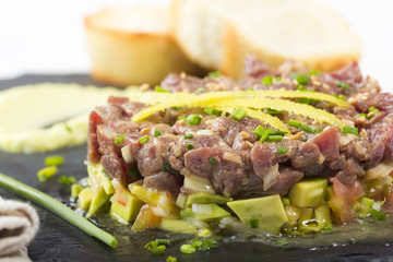 Bluefin tuna tartare on a black slate plate with avocado, served with grilled bread.