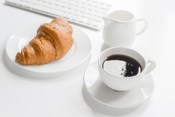 Businessman morning with keyboard, cup of coffee and croussant on white table background
