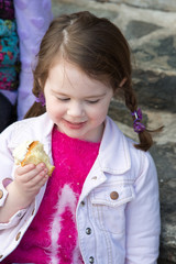 Young girl sitting outside eating a cupcake