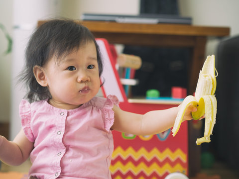 baby girl eating banana at home
