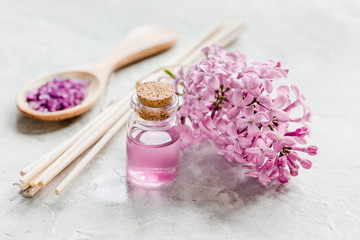 Fototapeta na wymiar take bath with lilac cosmetic set and blossom on stone table background