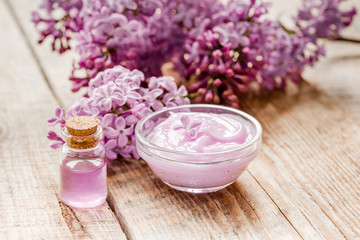 Obraz na płótnie Canvas lilac cosmetics with flowers and spa set on wooden table background