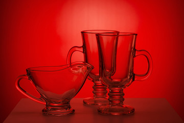 Transparent glass jug and glassfuls on red