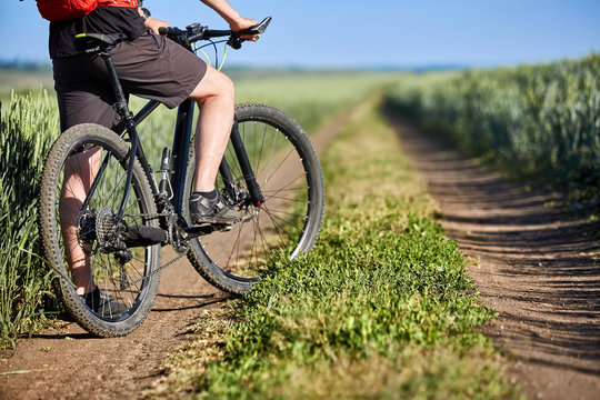 Close-up of cyclist man legs with mountain bike on the trail of field in the countryside.