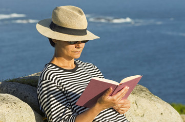 woman reading  book near to sea