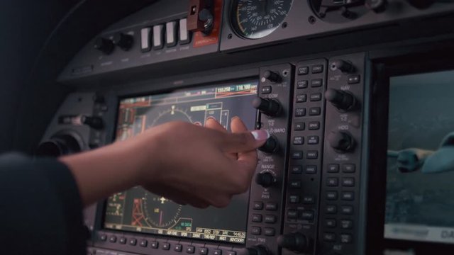 Navigation screen on plane control dashboard. Close up female hand tuning airplane navigation devices. Airplane navigation system. Cockpit instruments. Gps navigation system