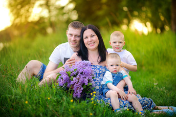 Fototapeta premium happy family on walk in the park on a sunset, sit on a grass and embrace
