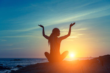 Fototapeta premium Yoga silhouette. Meditation woman on the ocean during amazing sunset.