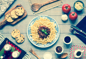 Fusilli pasta with tomato sauce, tomatoes, onion, garlic, dried paprika, olives, pepper and olive oil, on a wooden background.