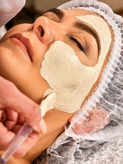 Collagen face mask. Facial skin treatment. Face of woman of elderly woman 50-60 years old receiving cosmetic procedure in beauty salon close up . Professional beautician. Removing wrinkles.