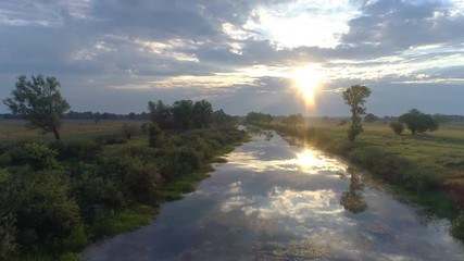 Flying over river at sunrise. Aerial shot. UHD, 4K
