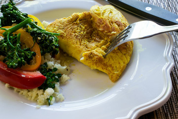 Closeup and selective focus on paleo dish of cauliflower Rice Stir-Fry on white plate, on bamboo placemat- eating healthy concept
