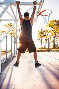 Basketball player hangs on the rim.attractive,laugh,sport games,street ball,black,sport outfit,casual wear,black clothes