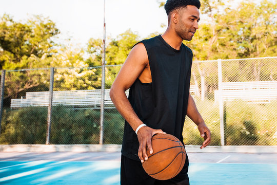 Basketball player holding ball.attractive,laugh,sport games,street ball,black,sport outfit,casual wear,black clothes