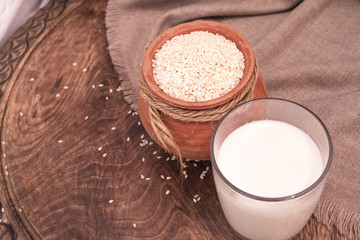 Sesame milk in glass and sesame seed in clay pot on a wooden table.