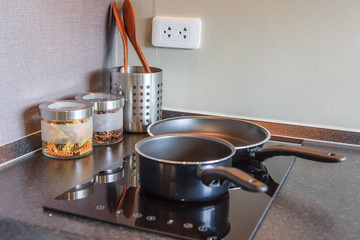 Black pan on Induction stove top panel in modern kitchen for cooking, closeup