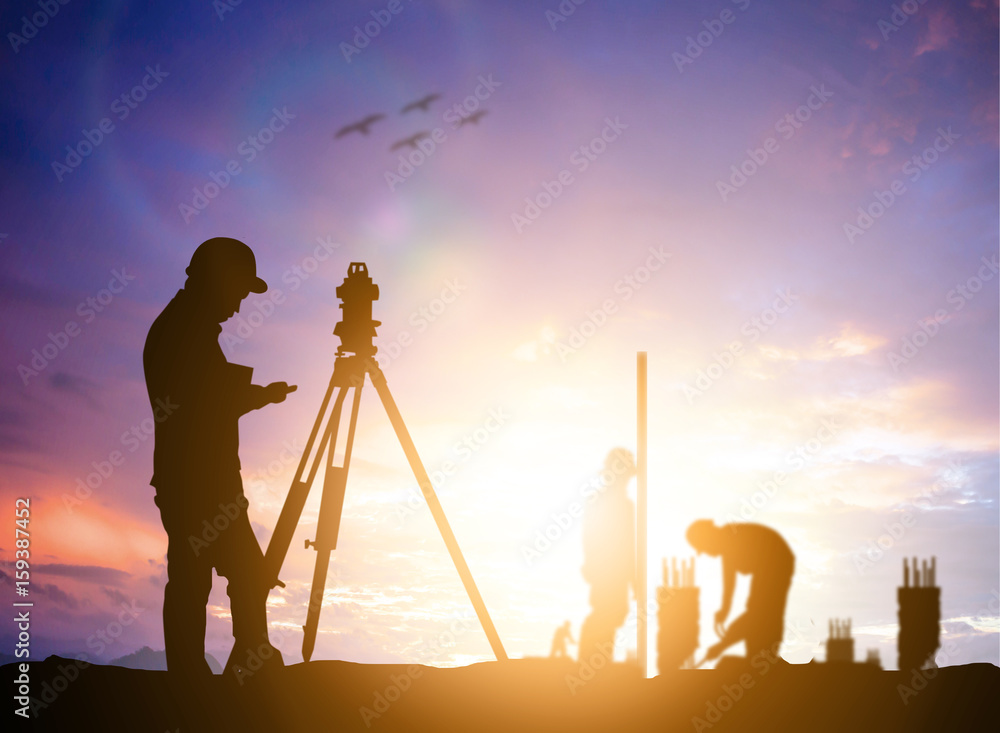 Wall mural silhouette survey engineer working in a building site over blurred construction worker on constructi