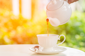 coffee pot pouring hot coffee into a cup during breakfast in morning sunlight