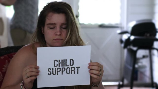 Frustrated woman holding up a child support sign with question mark