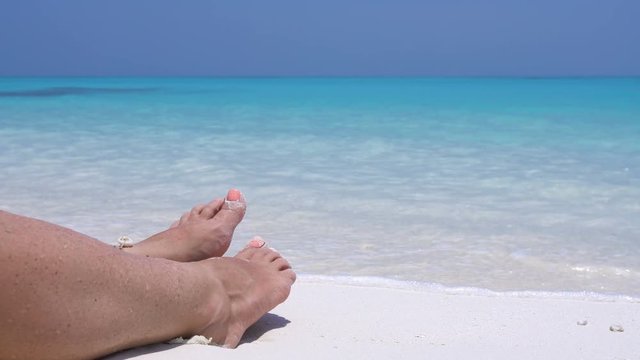 Female toe on sandy beach in caribbean sea waves. Tropical vacation 
