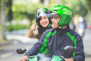 motorcycle taxi driver taking his passenger to her destination
