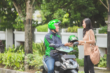 commercial motorcycle taxi driver giving helmet to his customer